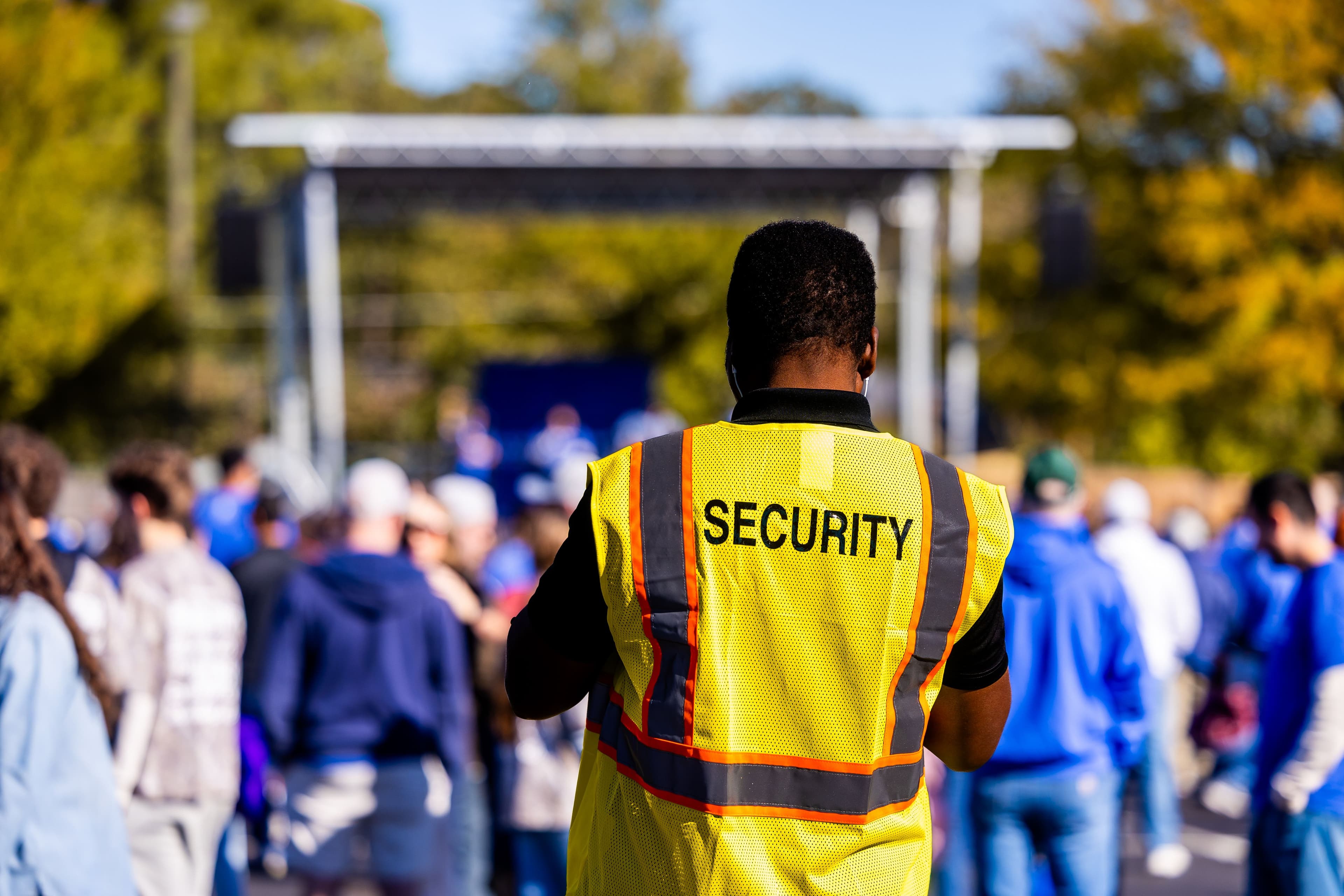 A security steward in a high-visibility vest overseeing an outdoor event