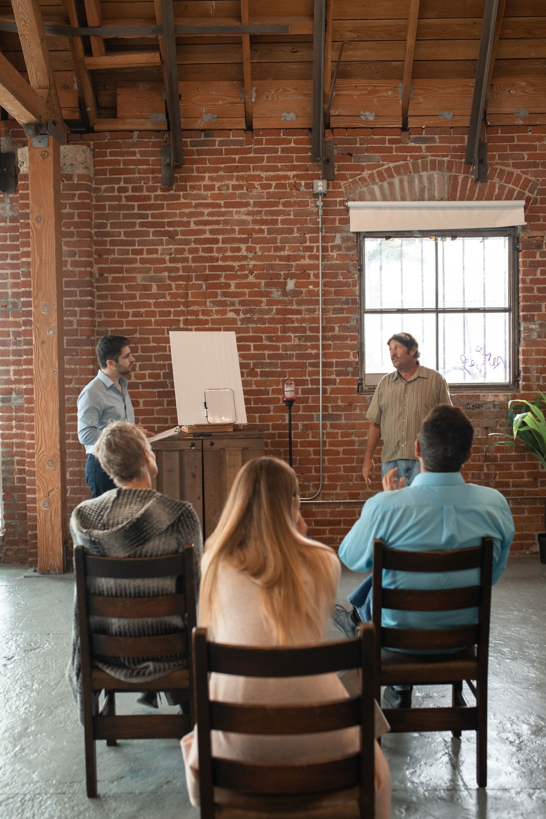 Adults seated in a training room facing two standing tutors