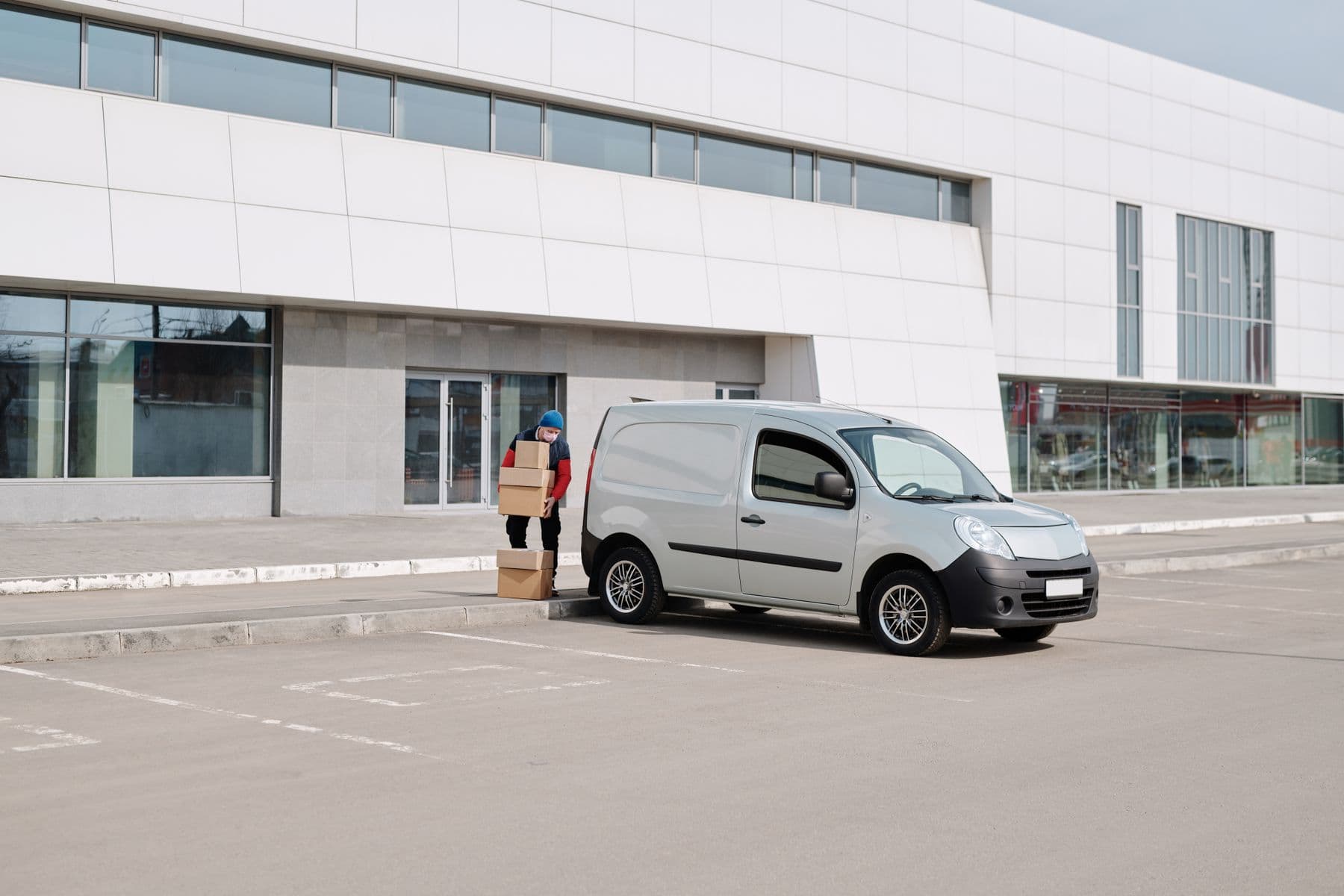 A worker handling cardboard boxes at the rear of a van