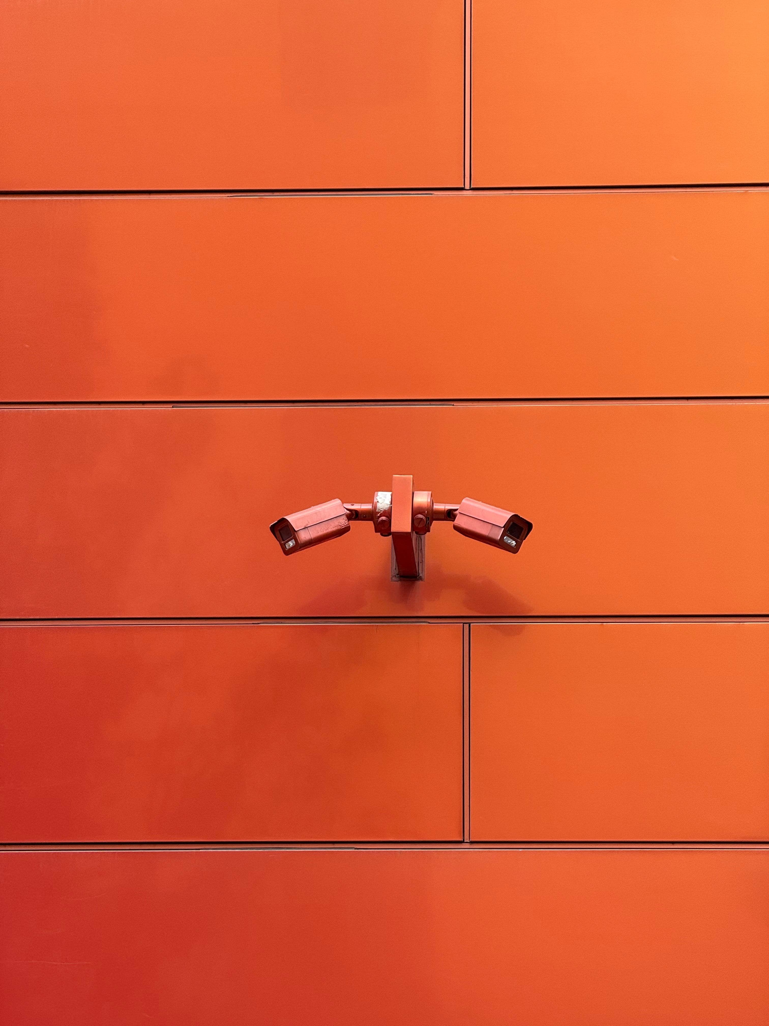 CCTV cameras on a minimalist orange wall